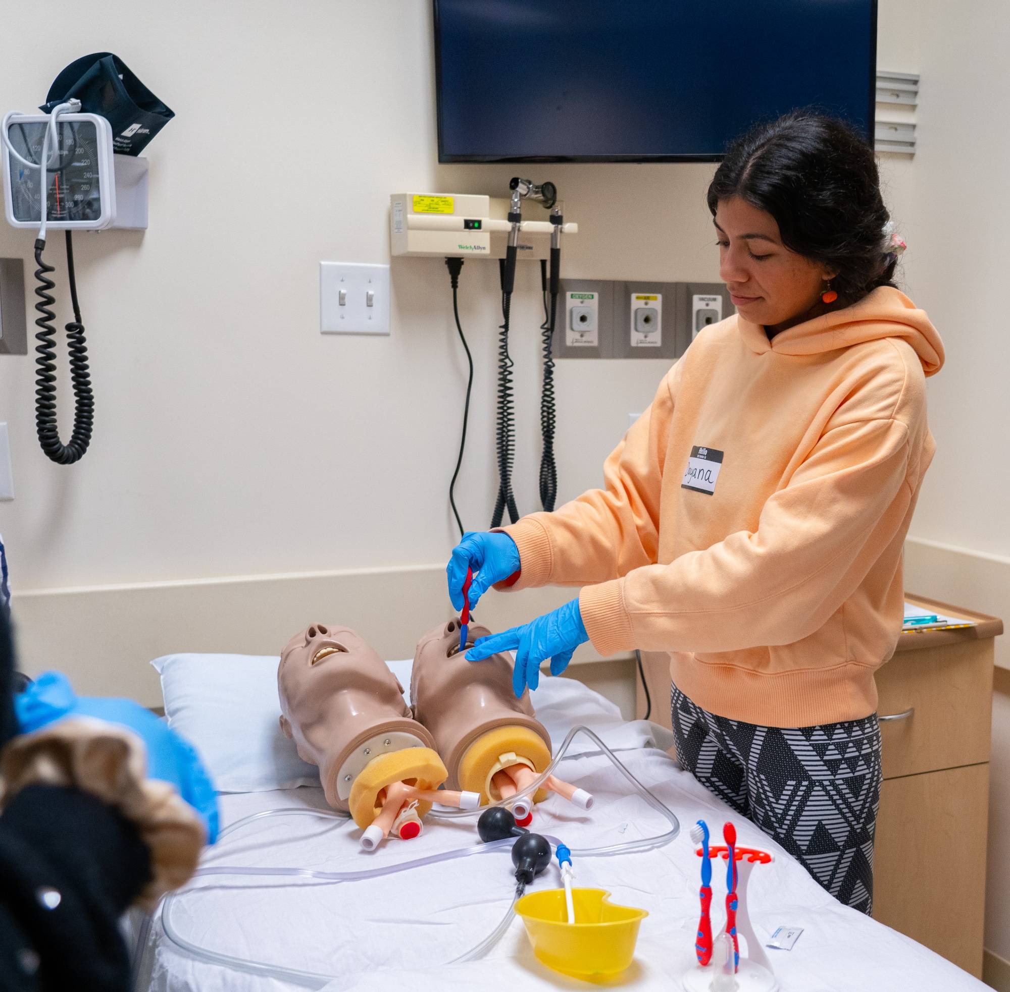 Students practicing oral care using suctioning system on a manikin head
